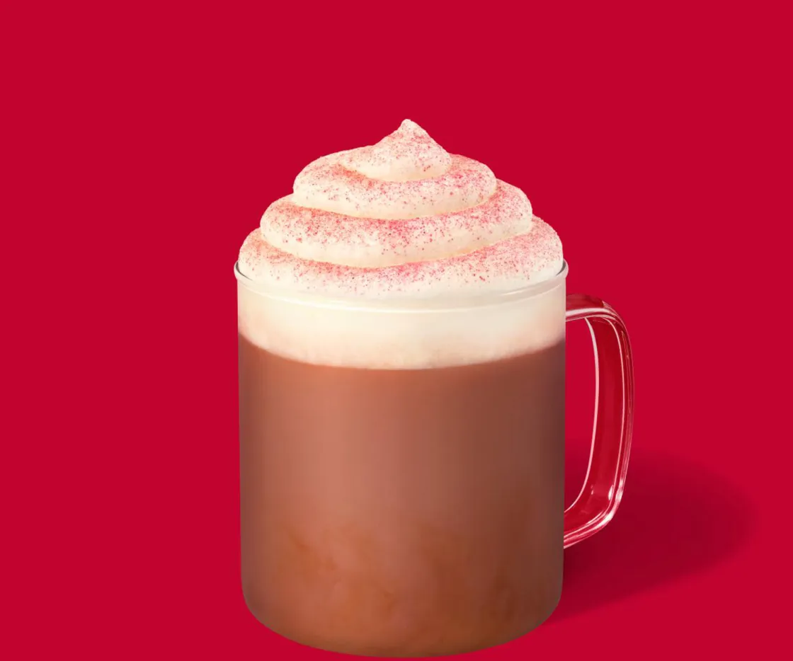 Red Velvet Latte quente com nata numa chávena de vidro, sobre um fundo vermelho