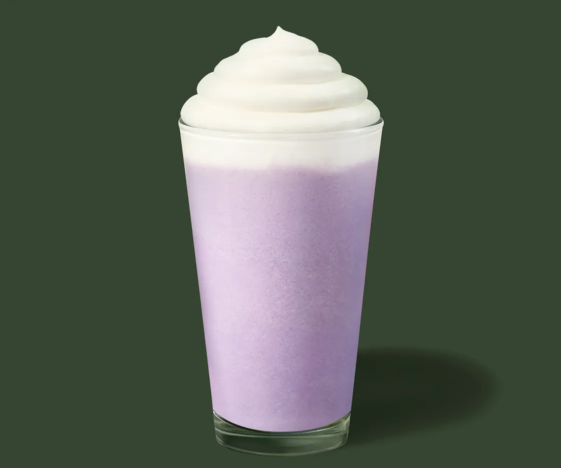 Um copo com Ube Vanilla Cream Frappuccino® sobre fundo verde